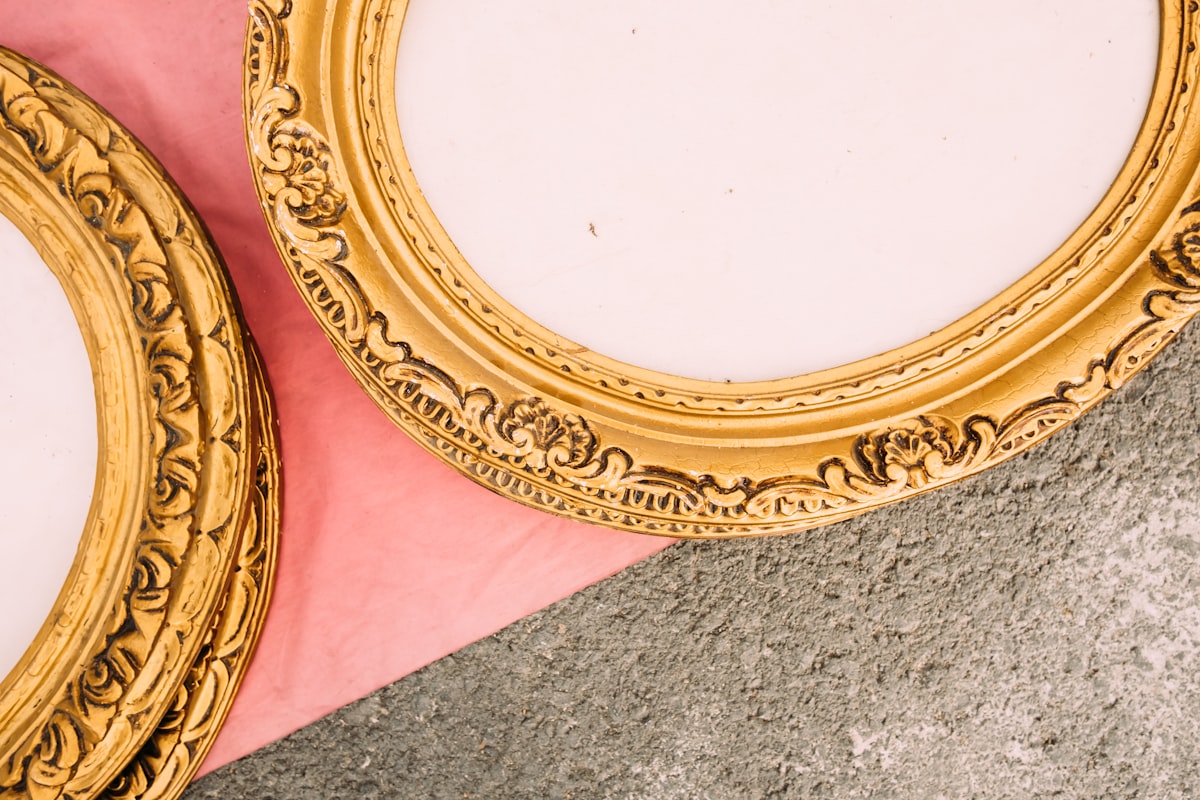 An arched gold-framed mirror leaning against a white wall in a bright room